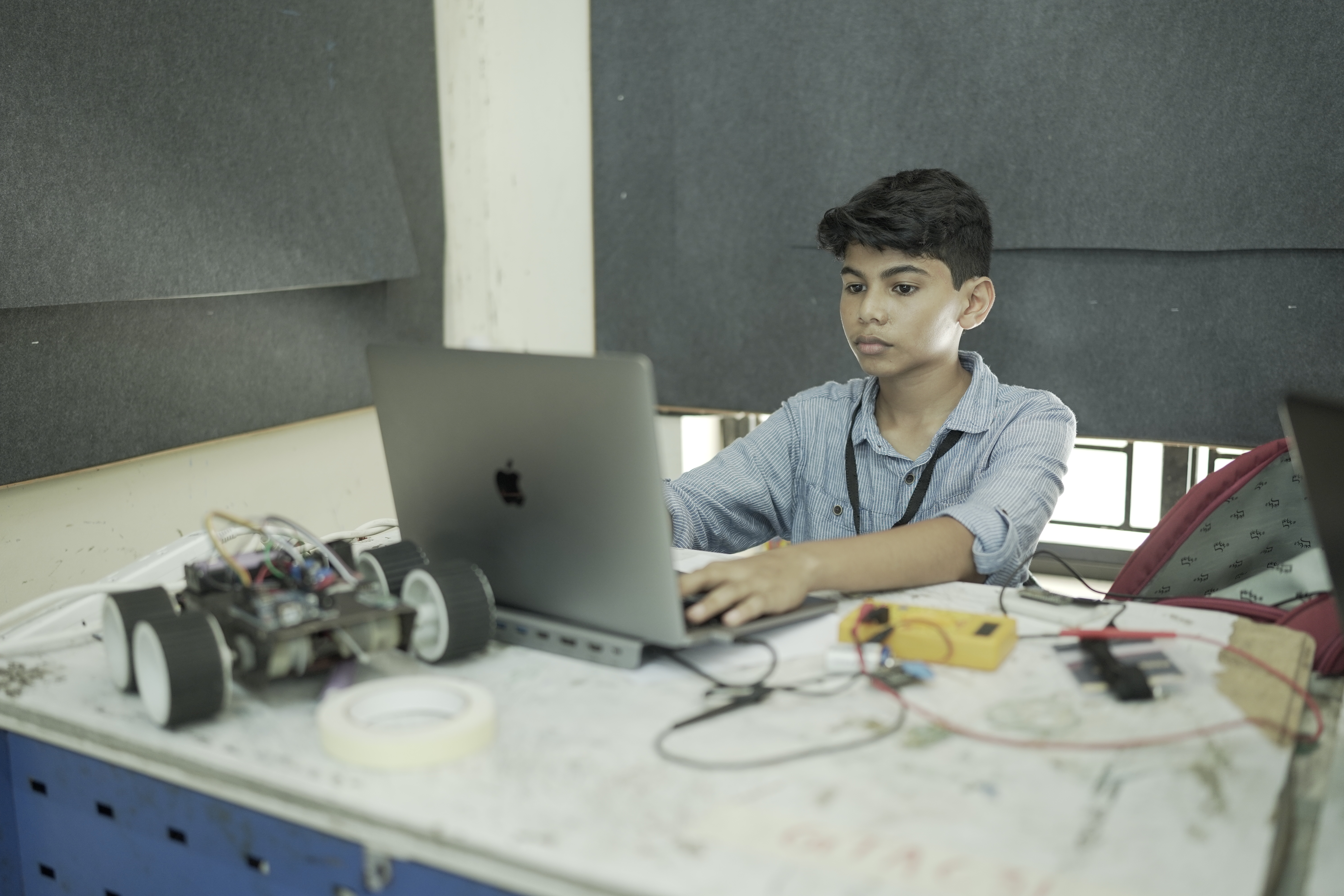 Riza Mohamed at workbench coding MacBook with electronics robotics Kerala India