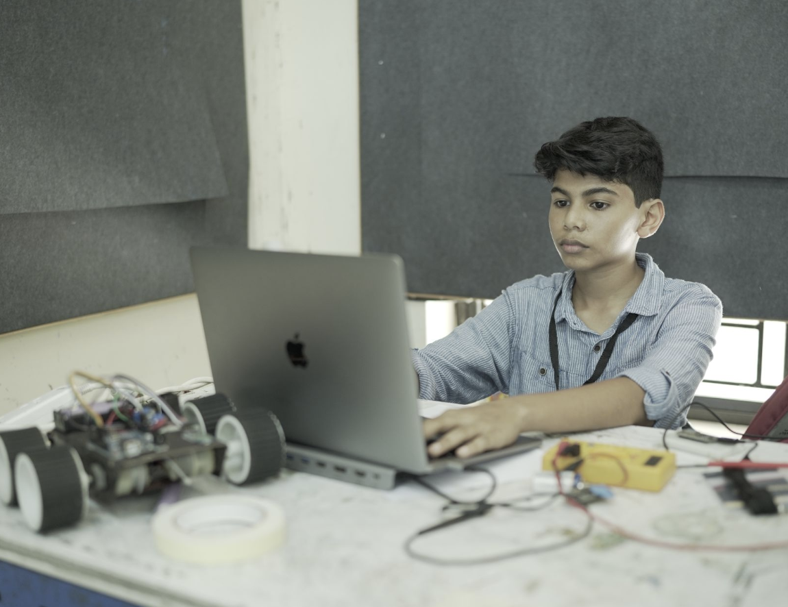 Riza Mohamed coding building robot at workbench