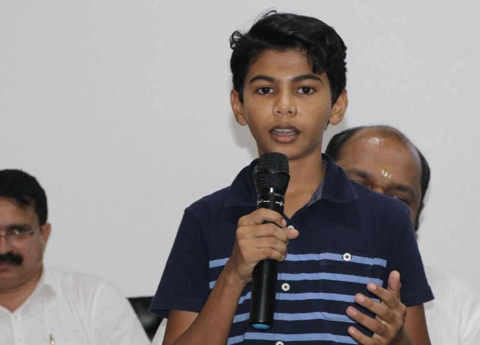 Riza Mohamed speaking at press conference with microphone Kerala India